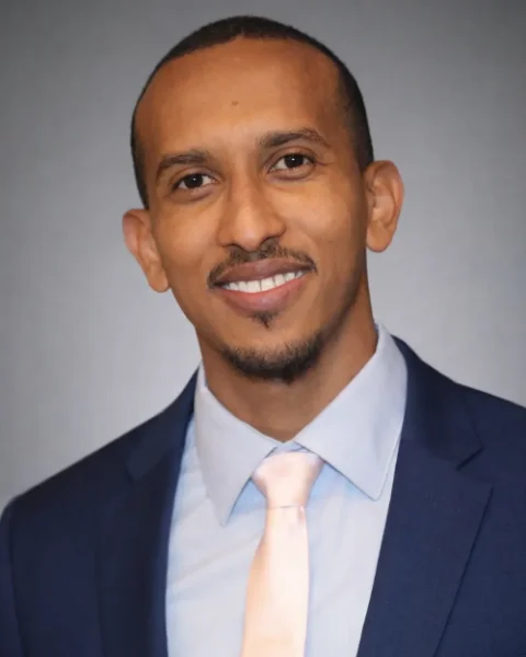 Mohamed Mohamed, PMHNP-BC, smiling, in a navy suit